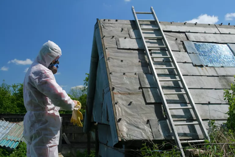 Asbestos removal worker. Dangerous waste disposal - professional works with old architecture.