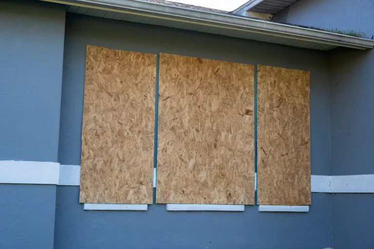 Boarded up windows with plywood storm shutters for hurricane protection of residential house. Protective measures before natural disaster in Florida.