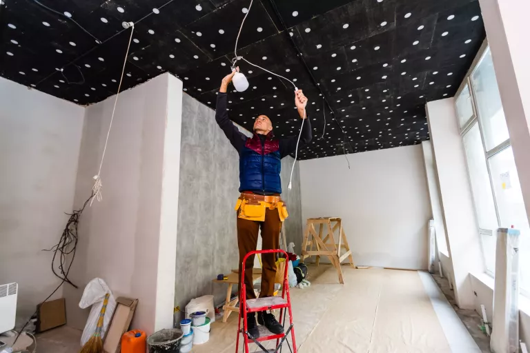 Electrician installer with a tool in his hands, working with cable on the construction site. Repair and handyman concept. House and house reconstruction